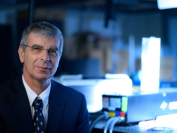 A man with gray dark hair wears a dark blue suit.