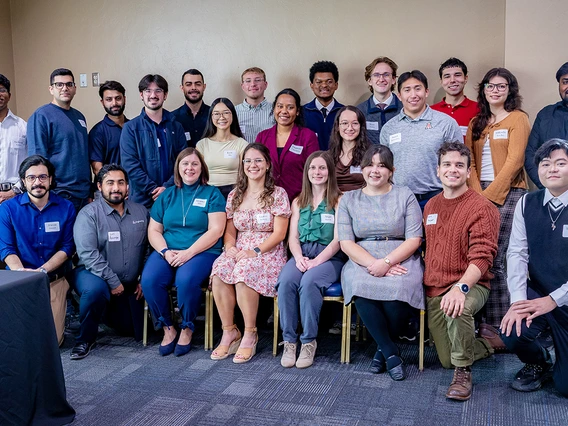 A large group of people in different colored clothing pose for a photo.