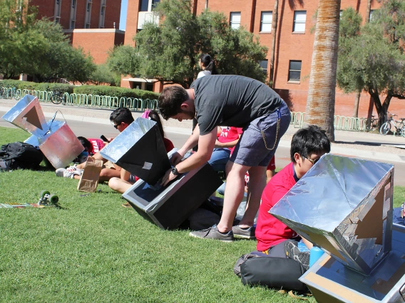 A student adjusts the settings of his team's solar oven.