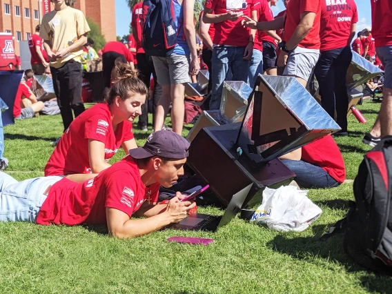 A student checks the rising temperature of his team's solar oven.