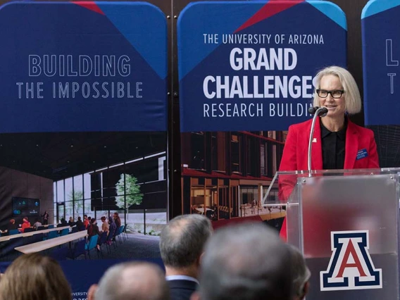 Betsy Cantwell stands at a podium in front of a crowd