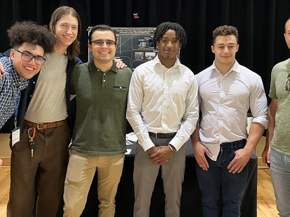 6 people stand in front of a research poster