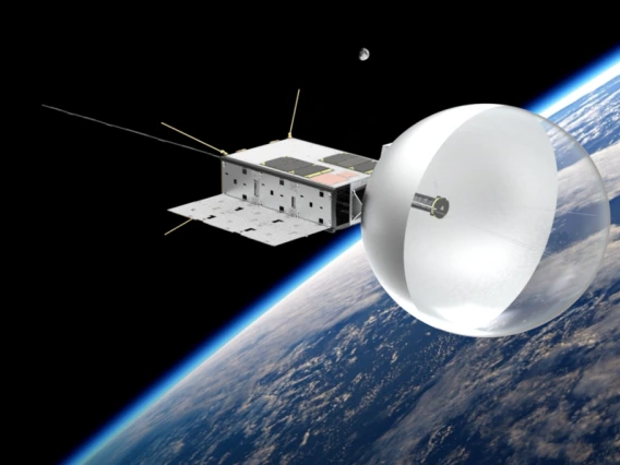 A cube-like box drifts around earth with a beach-ball like antenna on its right side.