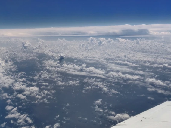A photo of the top of the cloud layer, taken from a plane. The wing of the plane is visible in the bottom right of the photo.