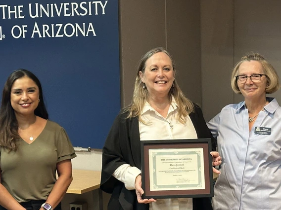 Three people pose with an award certificate