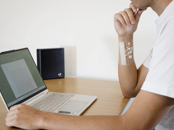 a person models the device while sitting at desk with a computer