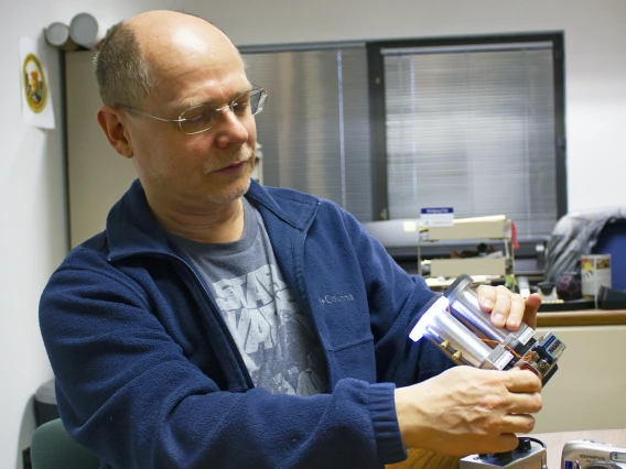 Wolfgang Fink holding up a metal, binocular-like device.