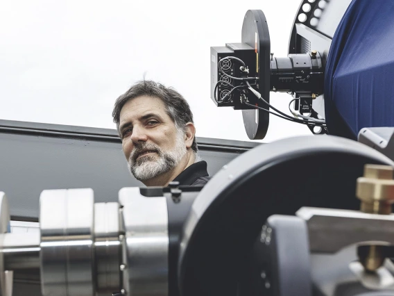 Roberto Furfaro standing behind a telescope