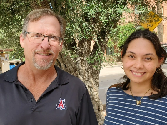 Greg Ogden and Carla Colon Cruz smile for a photo. They are outside in front of a tree.