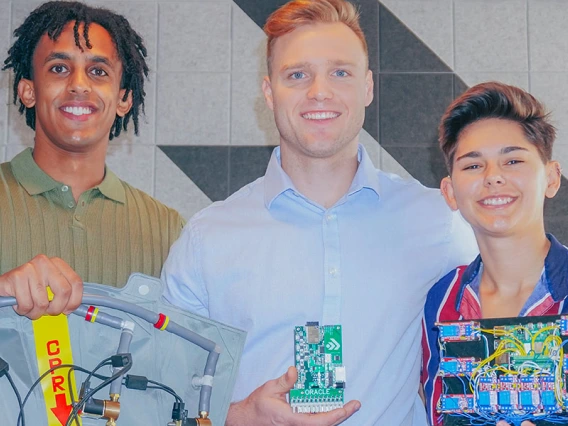 three people pose with computer parts