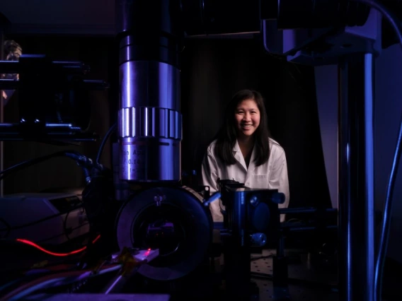 Judith Su in her lab with FLOWER. The lab is dark and lit with blue and purple lighting.