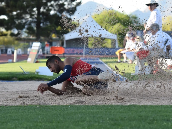 Mo Almarhoun sliding in the dirt after completing a long jump.