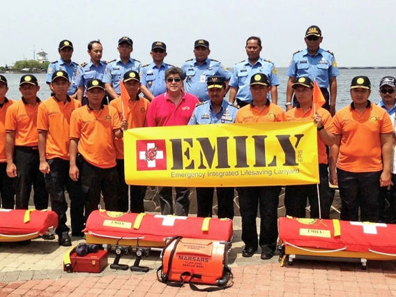 a large group of people pose near water with rescue equipment