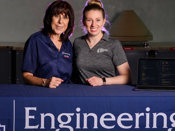 Sharon ONeal and Juliana Lincoln stand at a table with a laptop