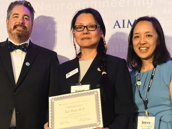 Three people pose with an award certificate