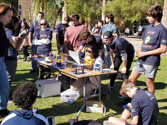 Students group around a table holding solar trackers