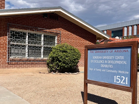 A red brick building is pictured with a blue sign in the front.