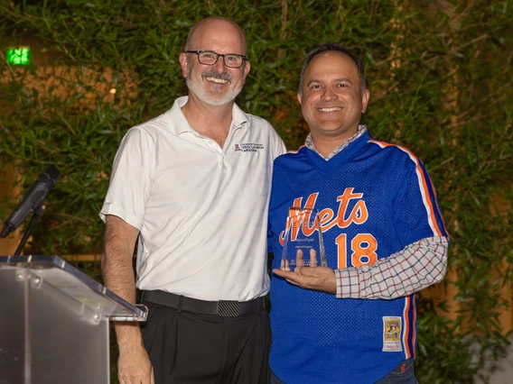 Two men stand at a podium with an award