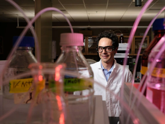 Andrea Achilli in his lab, with beakers in the foreground of the photo.