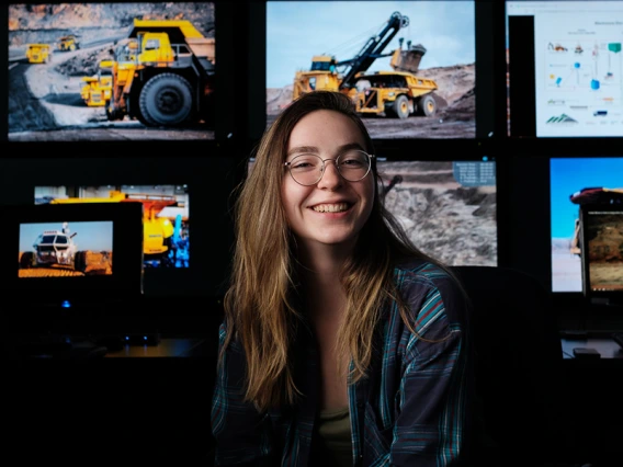 a student poses in front of several screens running mining software