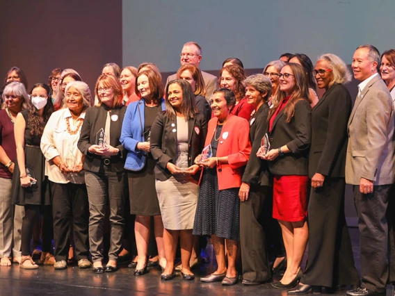 Women of Impact awardees stand on a stage