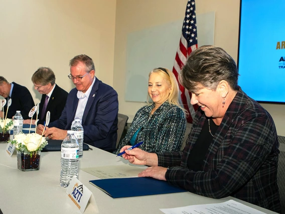 5 people sign documents at a table