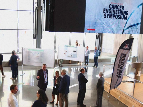 A small crowd of people in a large room with scientific poster displays