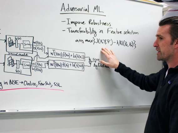 Gregory Ditzler explains a concept at a whiteboard.