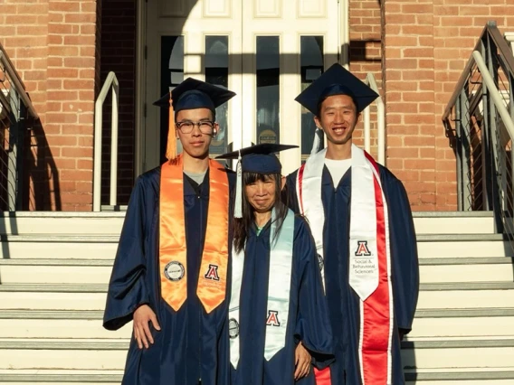 Three people pose on the steps of Old Main at the University of Arizona