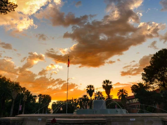 The sun sets over a fountain on the UA campus.