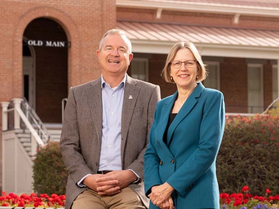 Two people sit in front of the Old Main building on the UA campus