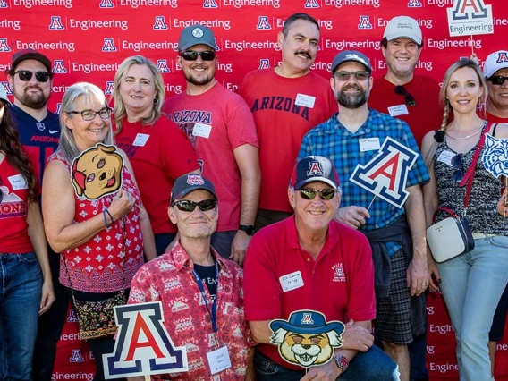 a group of people poses in front of a backdrop at the Homecoming tailgate