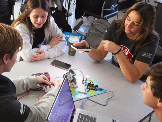 Four students test a small solar device in a classroom