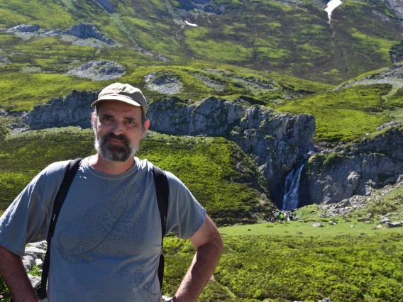 Jim Field on a hike smiling with a green landscape behind him