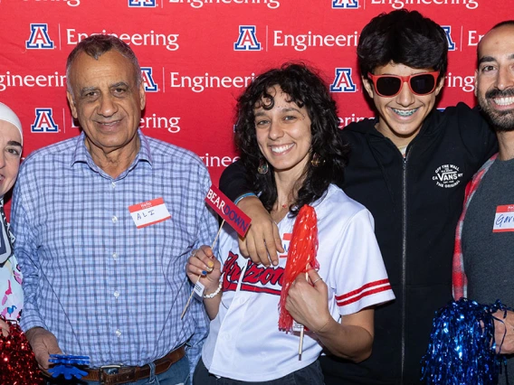 Five people pose in front of a photo background