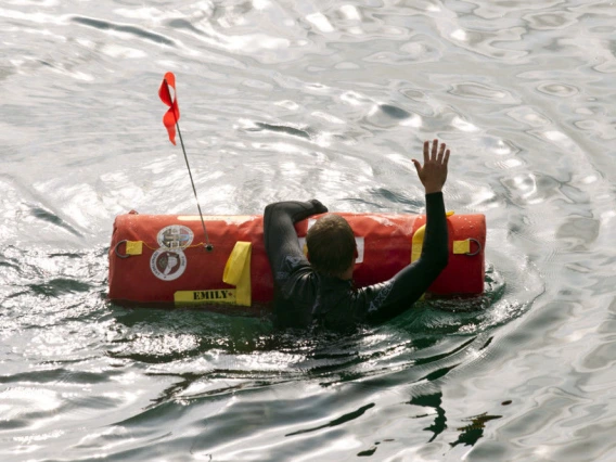 A swimmer in a wet suit holds onto an EMILY robotic rescue buoy