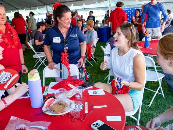 a group of students and faculty at an event table