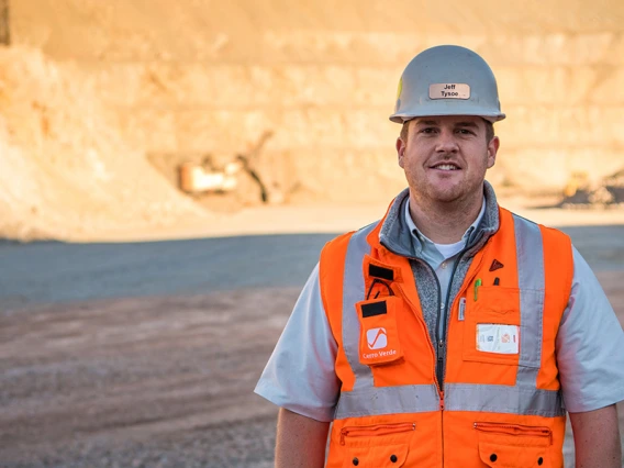 UA mining engineering alumnus Jeff Tysoe stands at the bottom of an open pit mine in a hardhat and orange safety vest