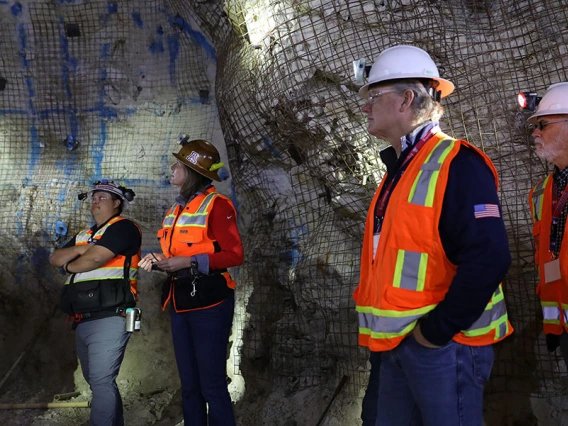 5 people wearing hard hats stand inside a mind