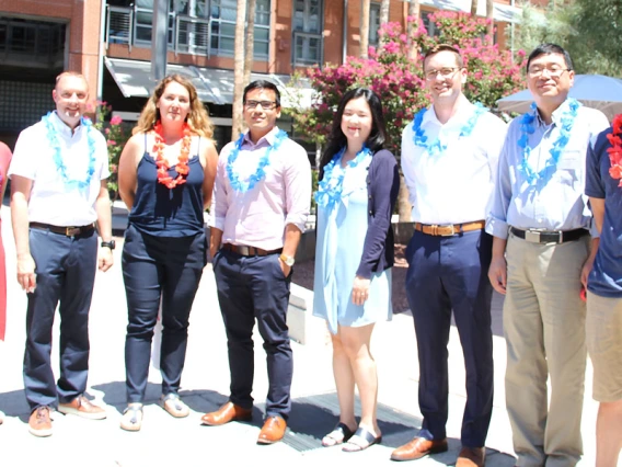 Eight faculty members smiling and wearing red and blue leis.