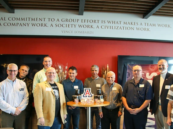 A group of 11 stands around a table holding award medallions