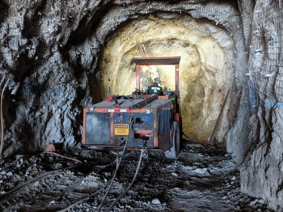 A piece of mining equipment preparing to bore into a gray rock wall