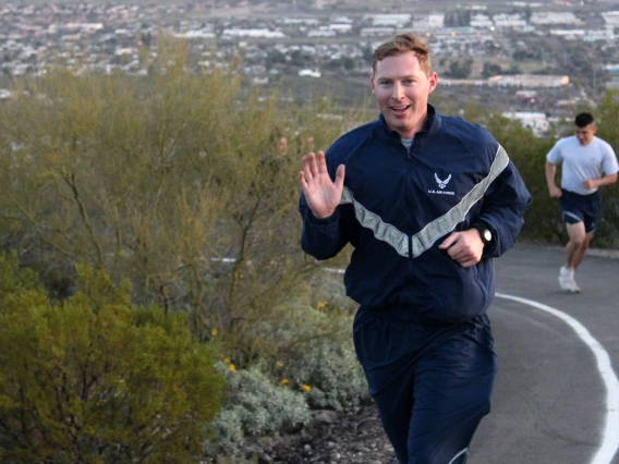 Ryan Raettig smiling and waving as he runs up Tumamoc Hill.