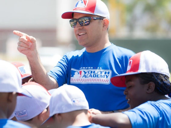 Ricardo Valerdi addresses a group of children in baseball caps outdoors