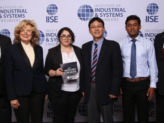 Six professionals pose for a photo in front of an IISE backdrop.