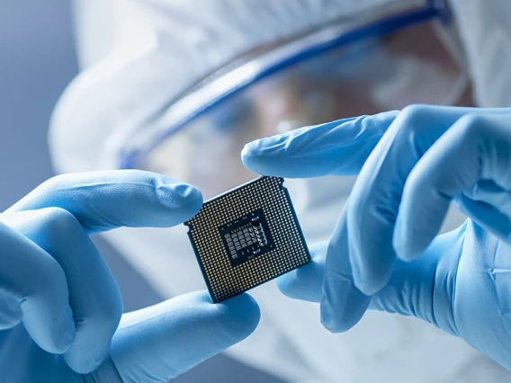 A gloved worker holds a computer chip