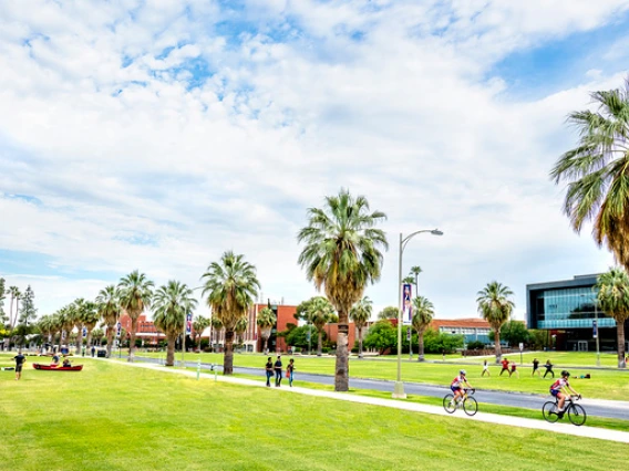 A shot of the UA Mall on a sunny day. Students are riding bikes and walking in the sunshine.