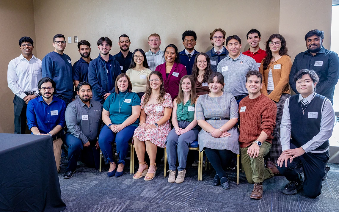A large group of people in different colored clothing pose for a photo.