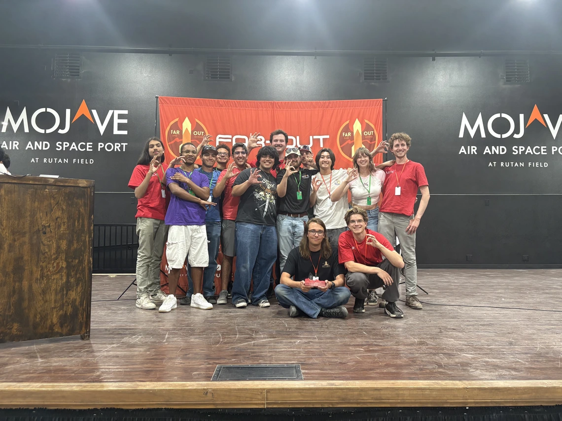 A group of students pose for a photo on a large stage.