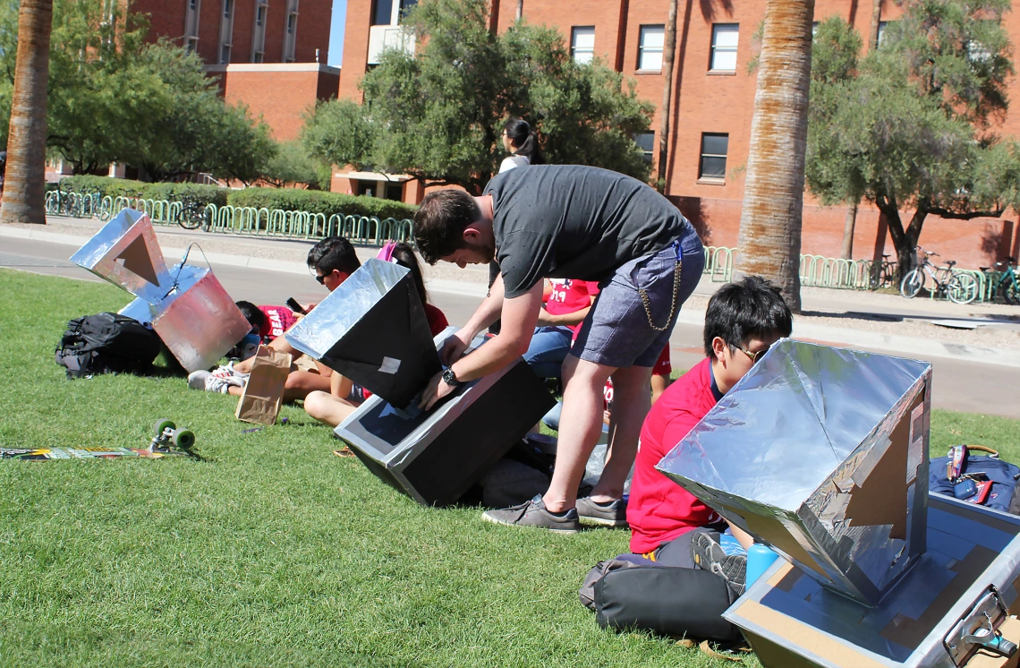 A student adjusts the settings of his team's solar oven.